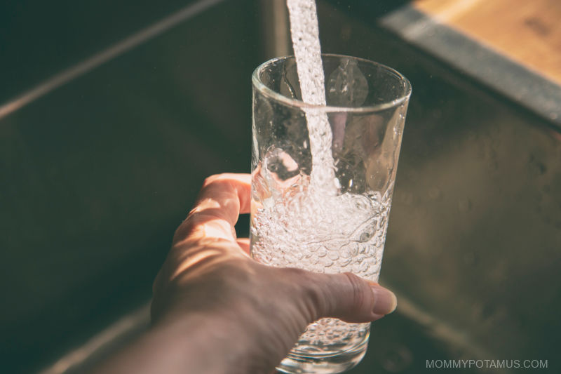 Pouring glass of water in sink