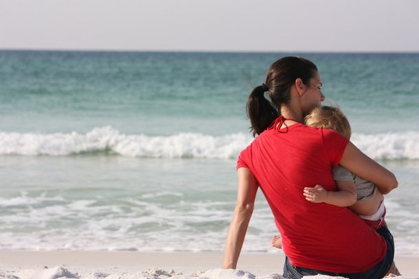 mom snuggling her son at the beach