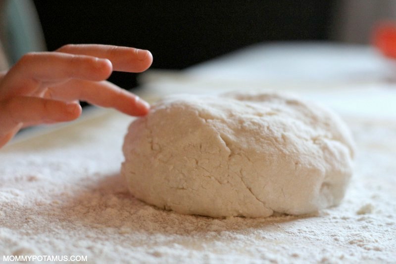 girl mixing water, flour, and salt in a mixing bowl