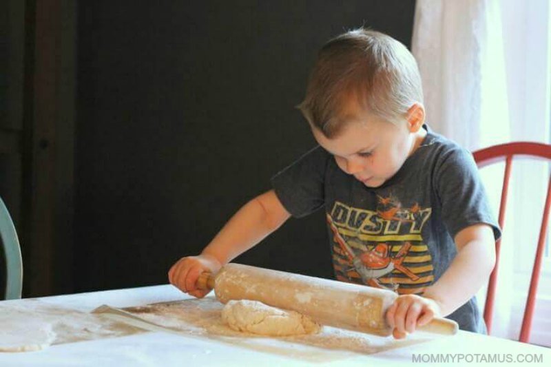 boy rolling out dough with a rolling pin