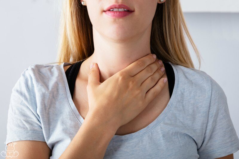 woman placing her hand over her throat to check her thyroid