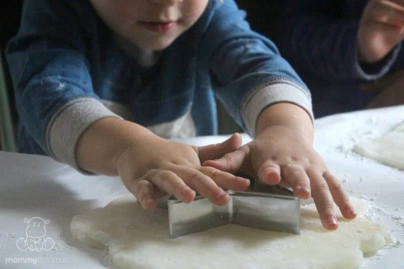 boy using cookie cutters to cut dough