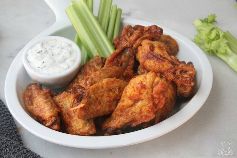 Crispy buffalo wings on plate with ranch dressing and celery sticks