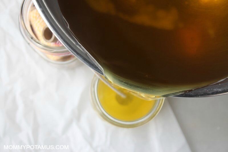 Pouring melted beeswax from metal bowl into candle jar