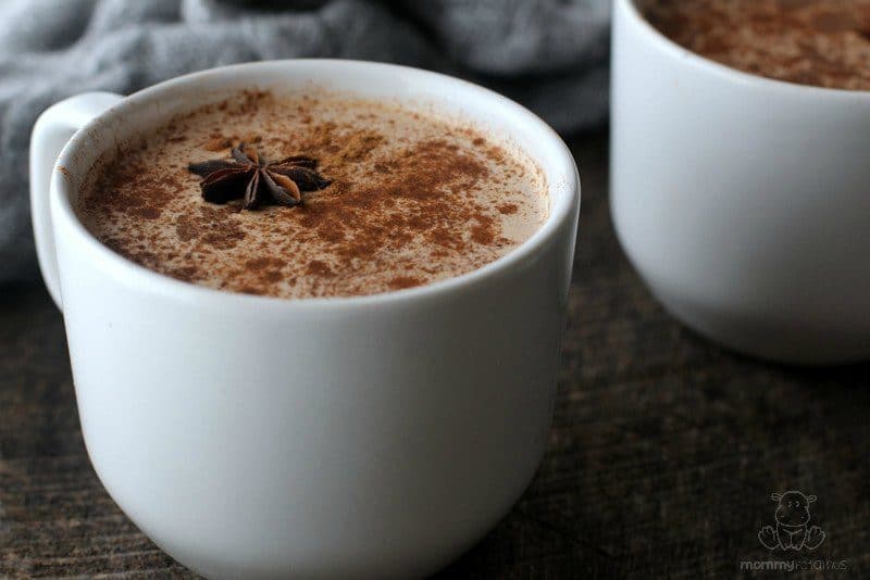 Cup of freshly brewed masala chai with ground cinnamon and one whole star anise on top. 