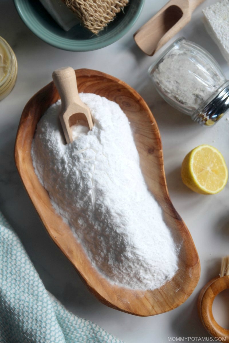 Overhead view of baking soda with lemon and scrub brush