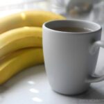 banana peel tea in a cup beside a bunch of bananas