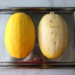 two halves of a spaghetti squash lying face down in a glass baking dish