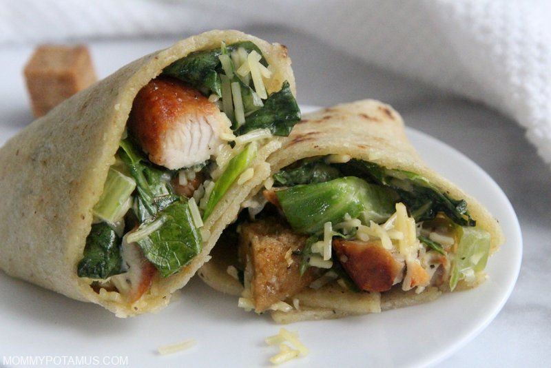 Close-up view of chicken caesar wrap cut in half on a plate.