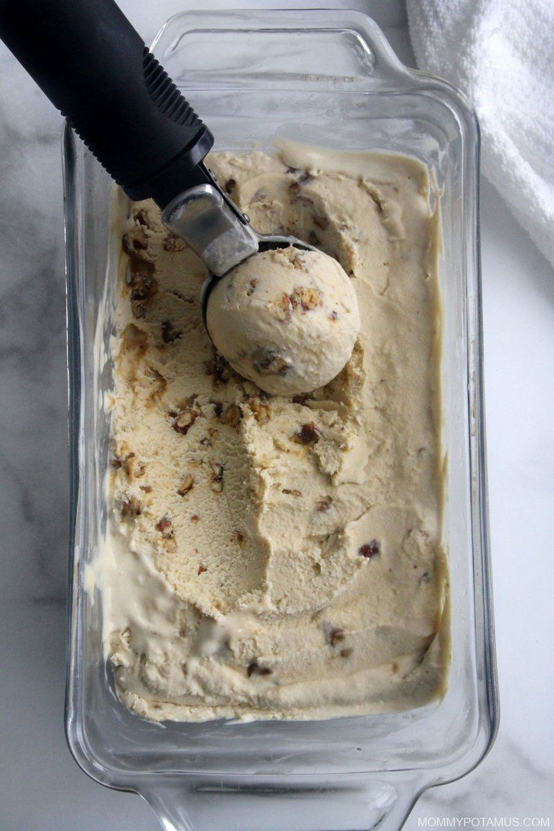 Scooping homemade butter pecan ice cream out of container.