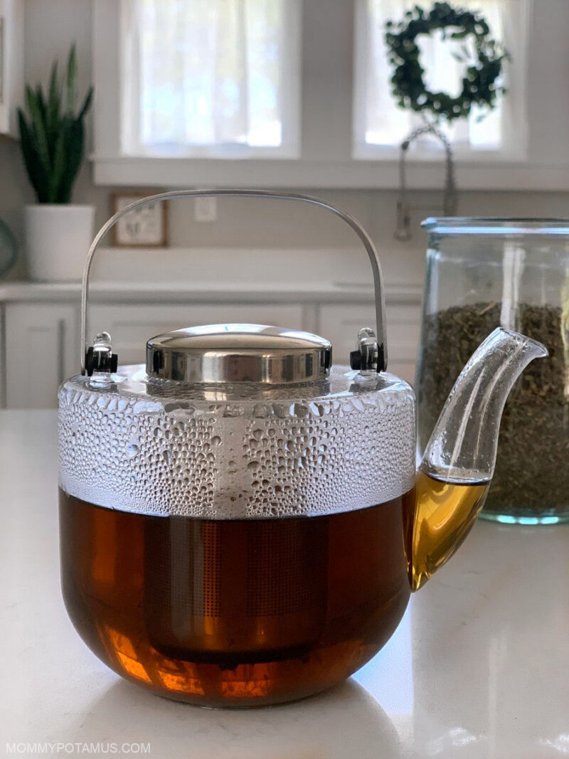 Close up of nette tea infusion steeping in clear glass teapot