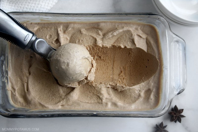 Overhead view of scooping homemade chai ice cream out of a square container. 