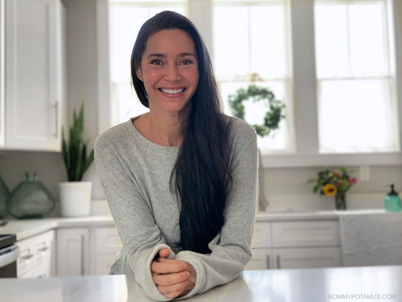 Woman leaning on kitchen counter in front of sink