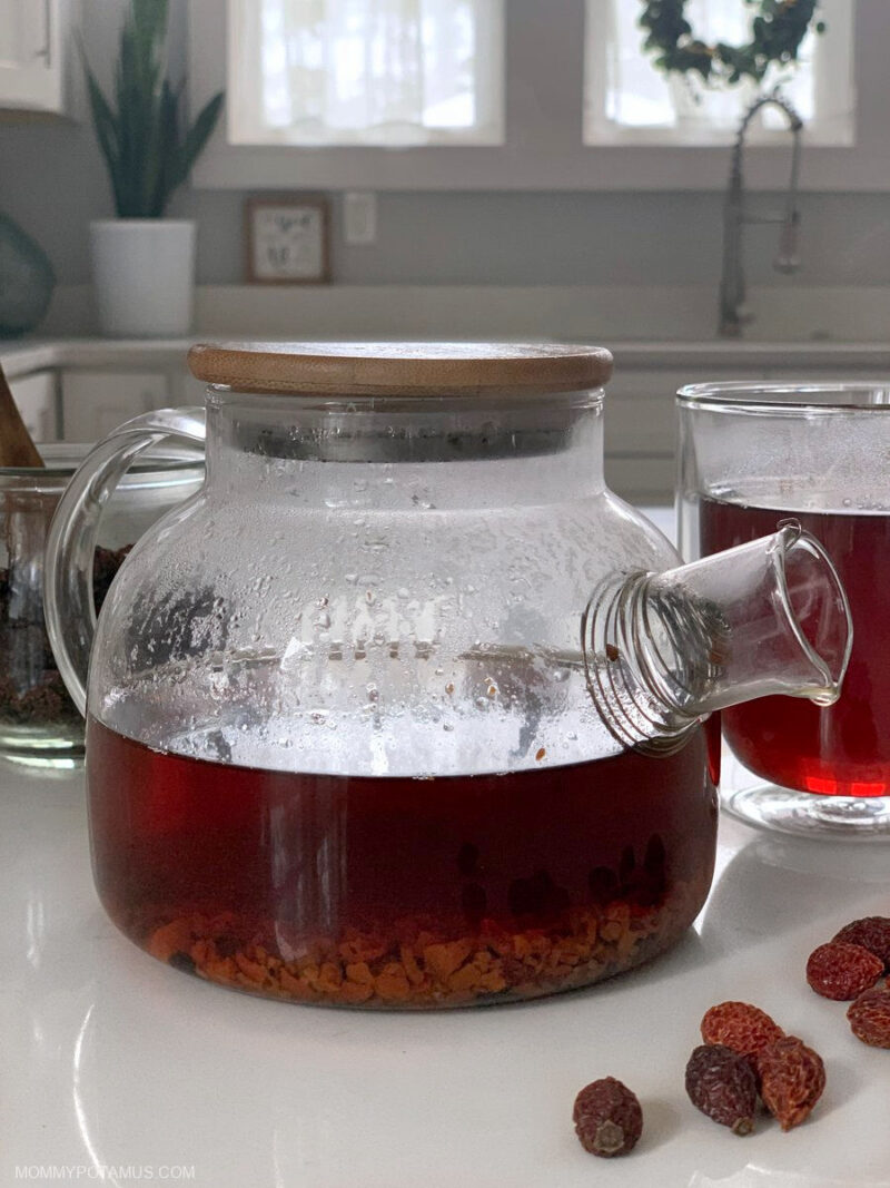 Glass teapot filled with rosehip tea on kitchen counter