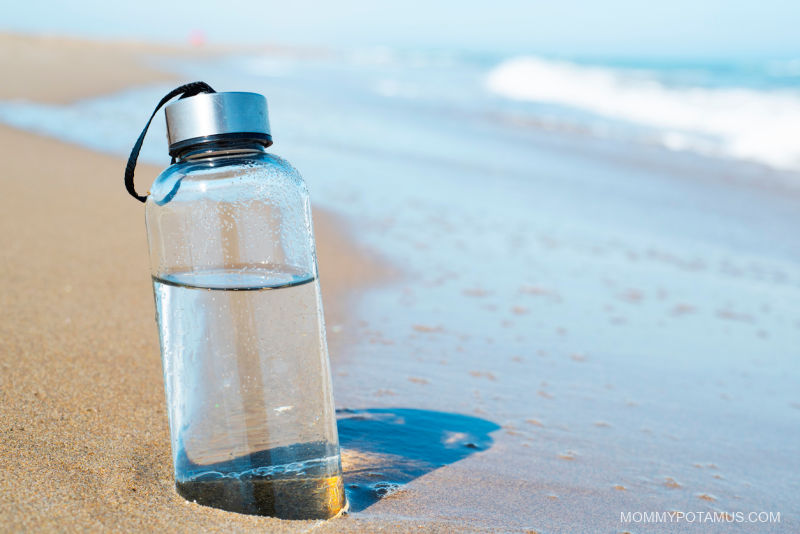 Glass water bottle on a sandy beach