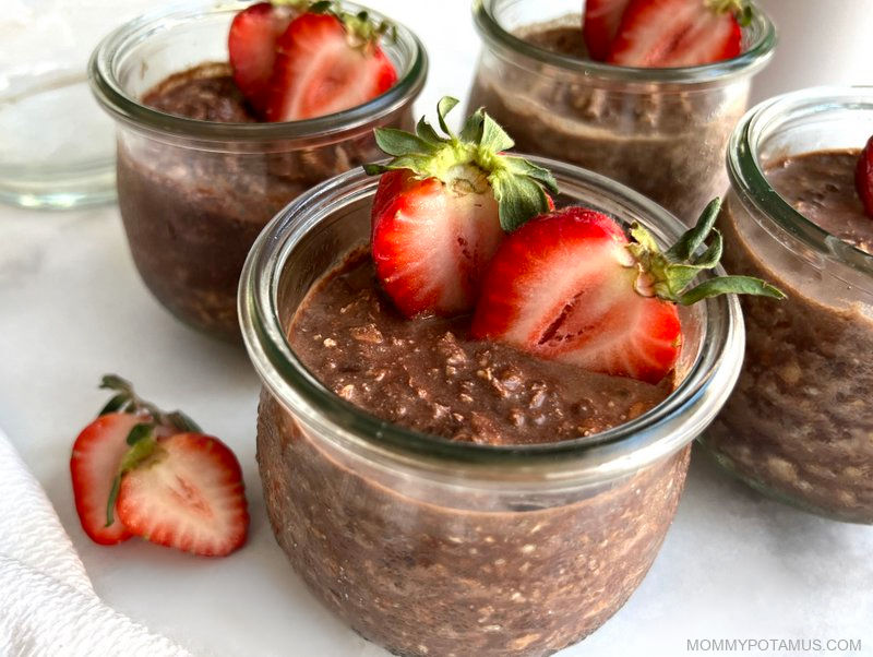 Four jars of overnight oats with strawberries on top/ 