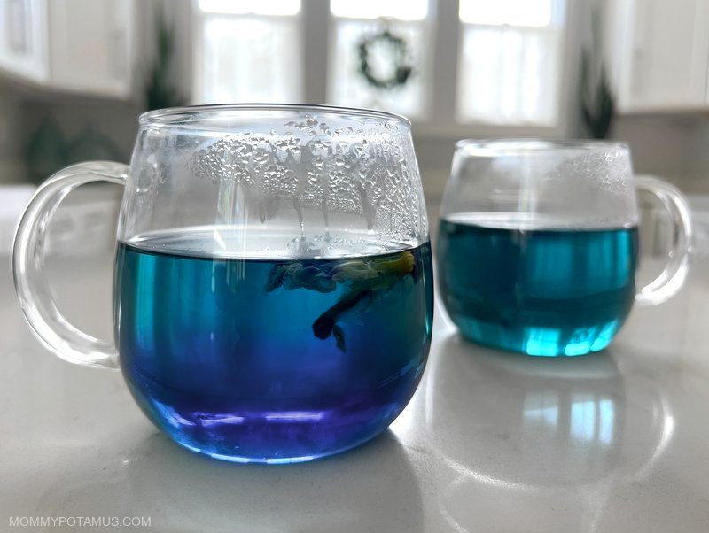 Cup of butterfly pea flower tea that has just had some lemon juice added. It's in the process of changing color and is part blue and part violet. 
