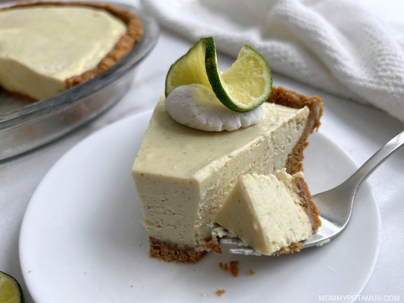 Slice of key lime pie on dessert plate with whipped cream and lime slice