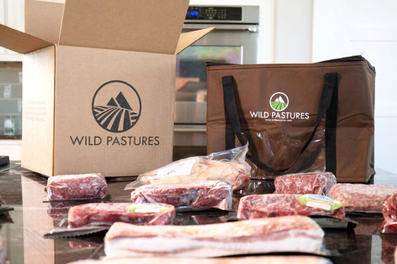 Wild Pastures box surrounded by meat on a kitchen counter. 