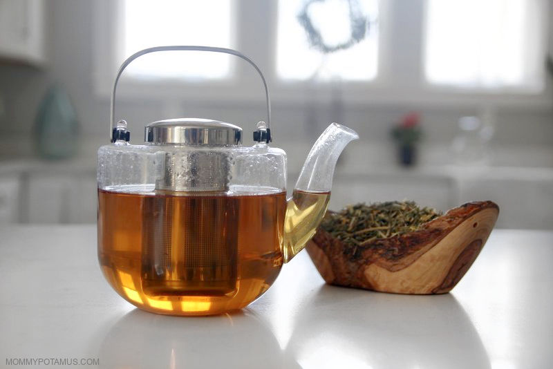 Glass kettle of California poppy tea next to bowl of dried herb