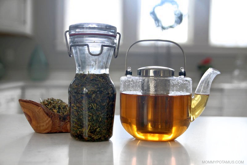 Glass kettle filled with California poppy tea, jar of California poppy tincture, and dried herb in bowl