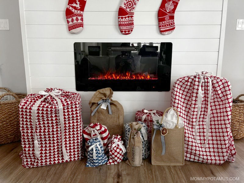 Gifts wrapped in front of fireplace with stockings hanging above