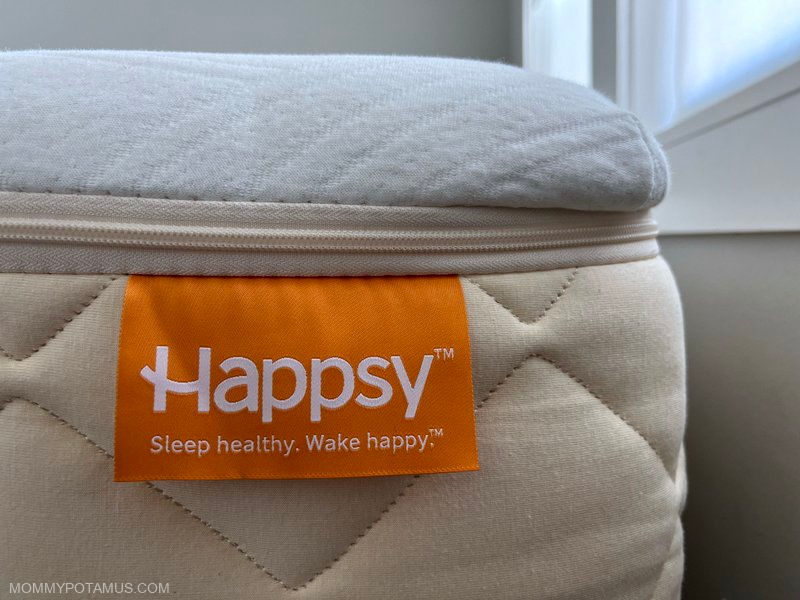 Up close view of Happsy mattress corner with bright orange Happsy tag. 