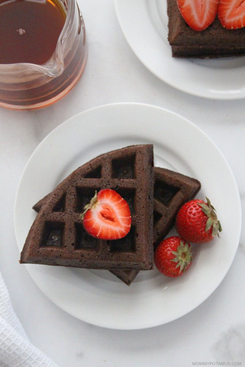 Overhead view of chocolate waffles on a plate with strawberries