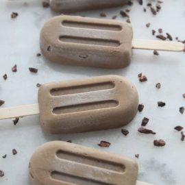 Homemade fudge popsicles on counter with cacao nibs