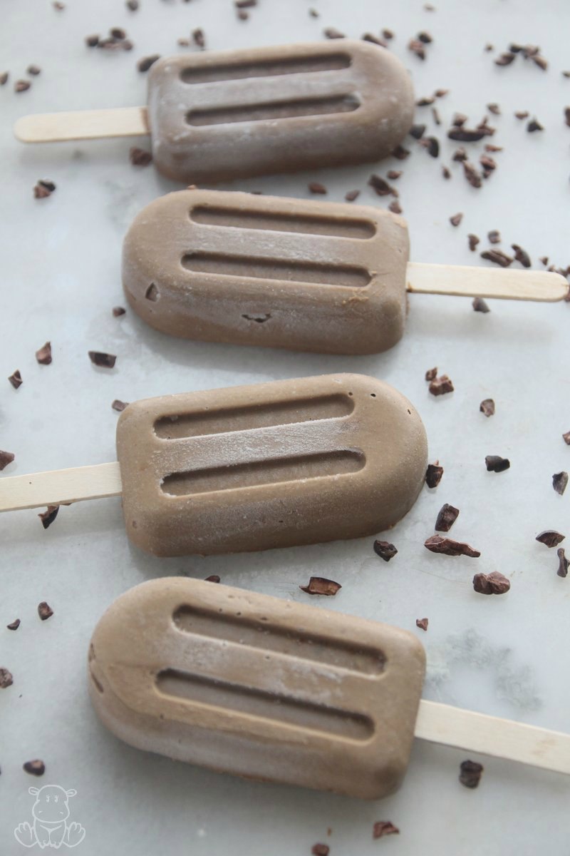 Homemade fudge popsicles on counter with cacao nibs