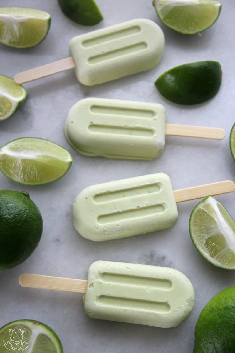 Vertical photo of key lime pie popsicles on marble surface