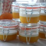 Jars of homemade gelatin cups on counter next to oranges