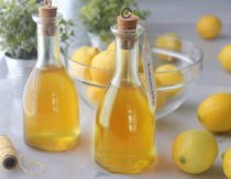 Bottles of homemade limoncello on counter with lemons