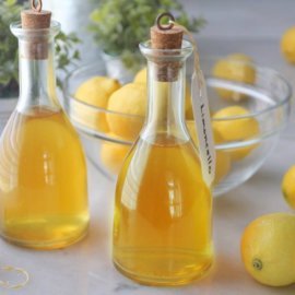 Bottles of homemade limoncello on counter with lemons