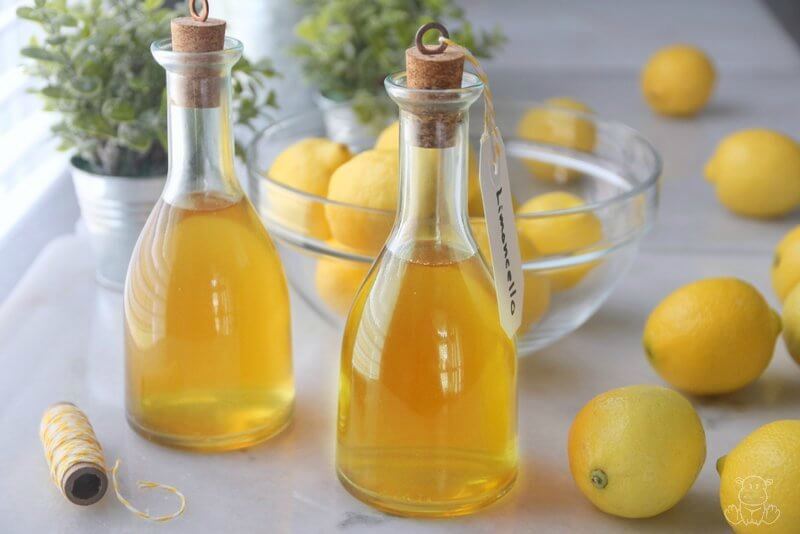 Bottles of homemade limoncello on counter with lemons